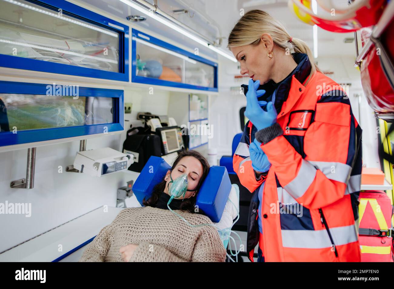 Rescuer taking care of patient, preparing her for transport. Stock Photo