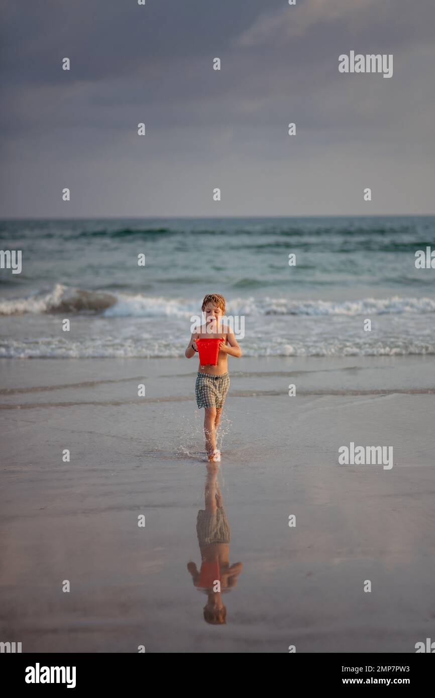 Little boy in swimsuit running out of sea, enjoying holiday. Stock Photo