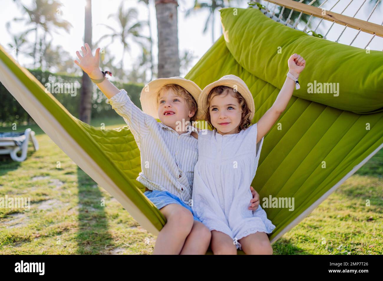 Little friends enjoying holiday in exotic country, lying in hammock. Stock Photo