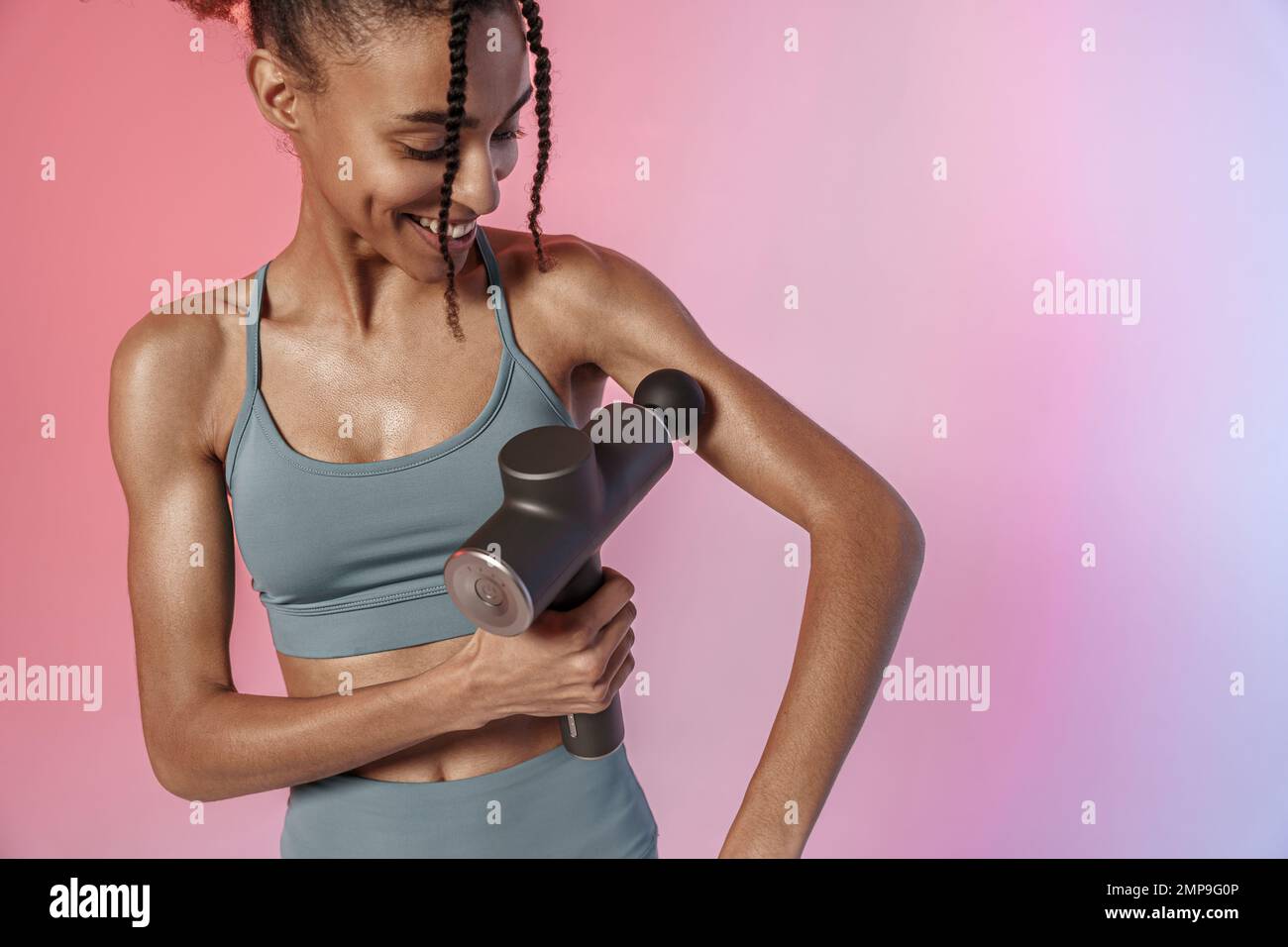 Woman use massage gun machine rehab after muscle workout standing on