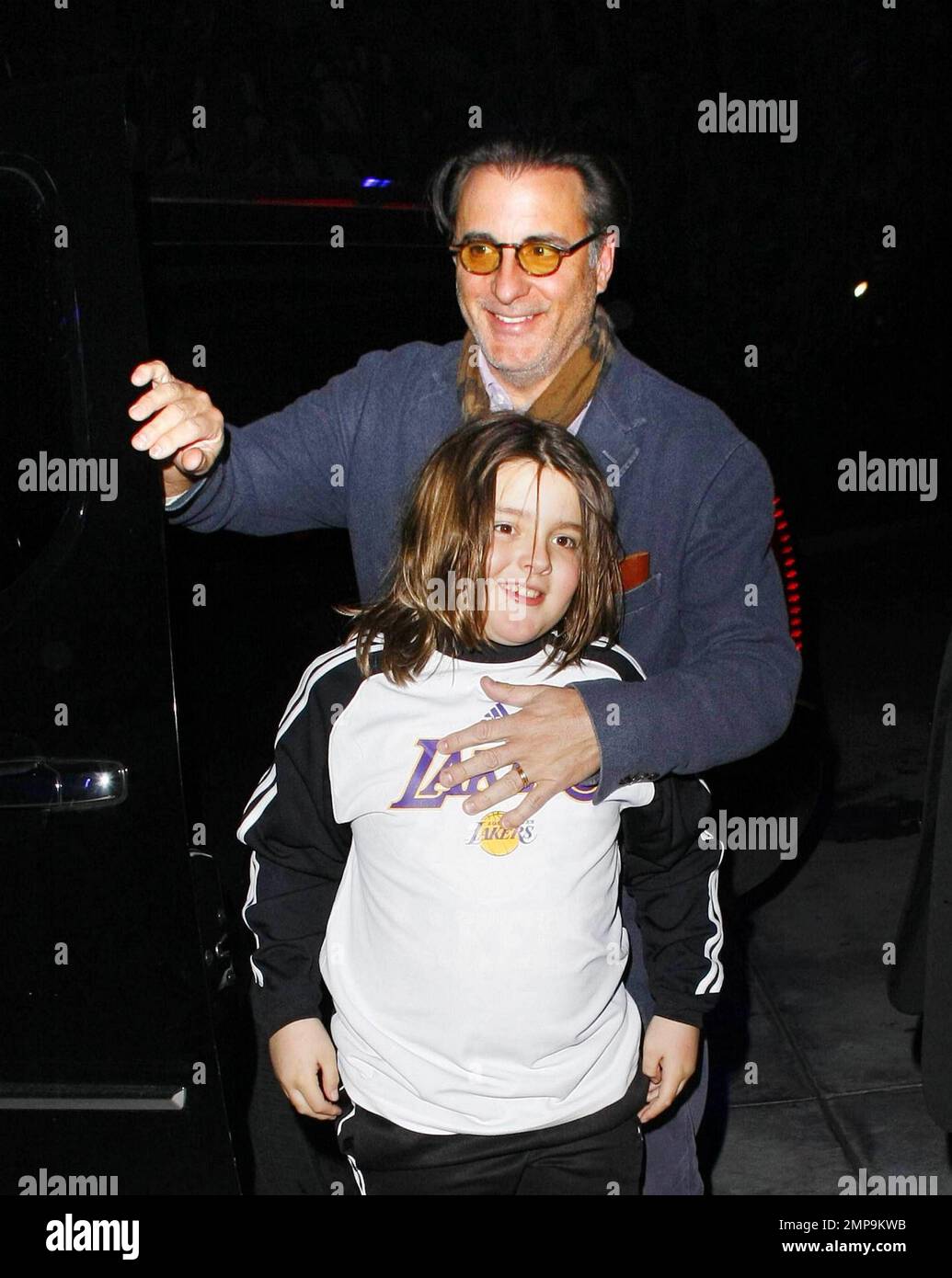 Andy Gardia and son Andres, 8, arrive in an SUV at the Staples Center to watch the LA Lakers vs. Houston Rockets basketball game.  Andy protectively held Andres, who wore a Lakers shirt, close as they smiled and made their way inside where they watched the Lakers beat the Rockets 114-106.   Los Angeles, CA. 02/01/11. Stock Photo