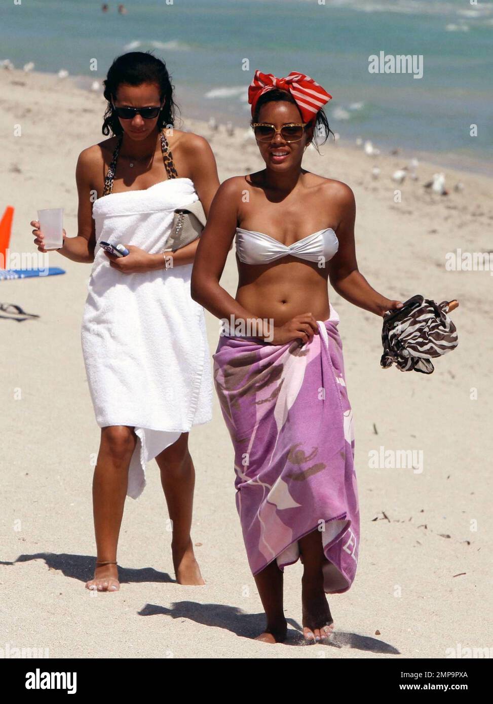 American socialite and entrepreneur, Angela Simmons, best known as the daughter of Run-D.M.C.'s Rev Run and neice of hip-hop legend Russell Simmons, wears a silver bikini paired with a floppy red scarf on her head as she spends an afternoon with a friend soaking up the sun on trendy South Beach. Angela looked like she had a blast while jet skiing and donned a zebra-print cover-up as she strolled with her friend on the sand. Miami Beach, FL.  3/1/11. Stock Photo