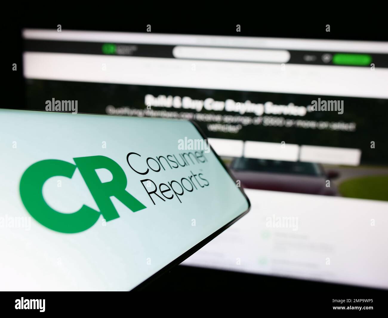 Cellphone with logo of American organization Consumer Reports (CR) on screen in front of website. Focus on center of phone display. Stock Photo