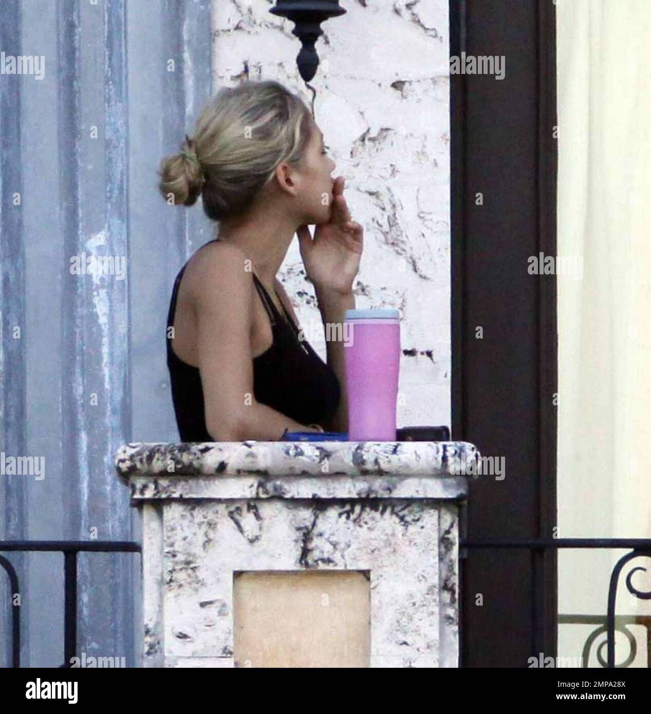 EXCLUSIVE!! Despite recent rumors of pregnancy, Anna Kournikova was spotted  on the balcony of her beleaguered home smoking a cigarette and looking at  her figure in the reflection of a glass door