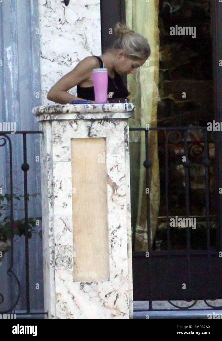 EXCLUSIVE!! Despite recent rumors of pregnancy, Anna Kournikova was spotted  on the balcony of her beleaguered home smoking a cigarette and looking at  her figure in the reflection of a glass door