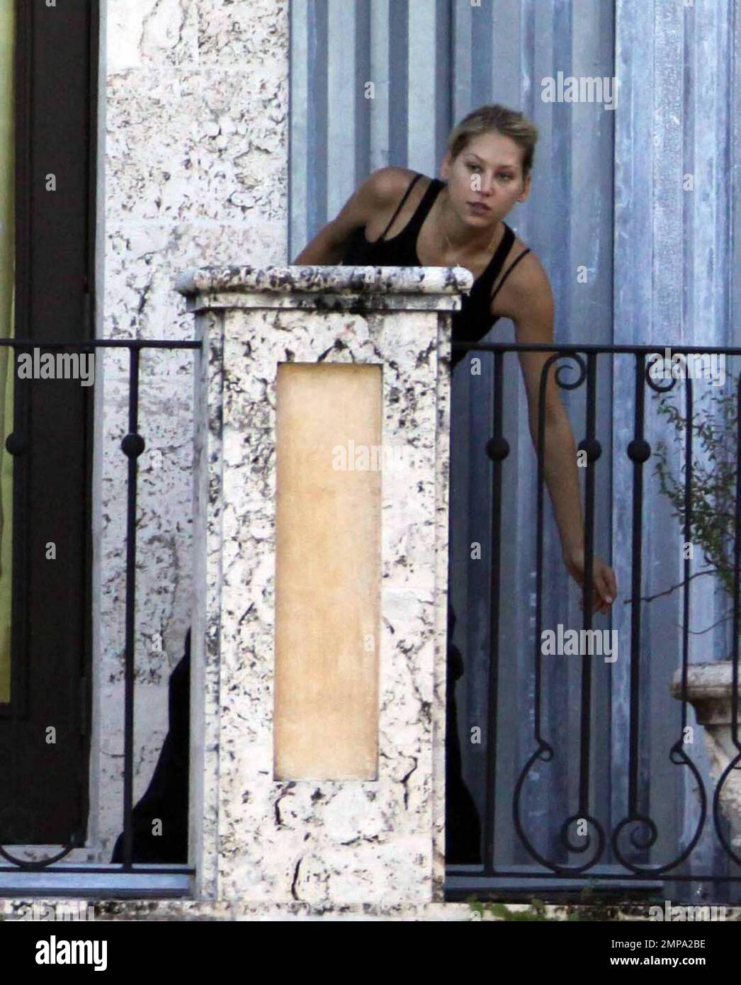 EXCLUSIVE!! Despite recent rumors of pregnancy, Anna Kournikova was spotted  on the balcony of her beleaguered home smoking a cigarette and looking at  her figure in the reflection of a glass door