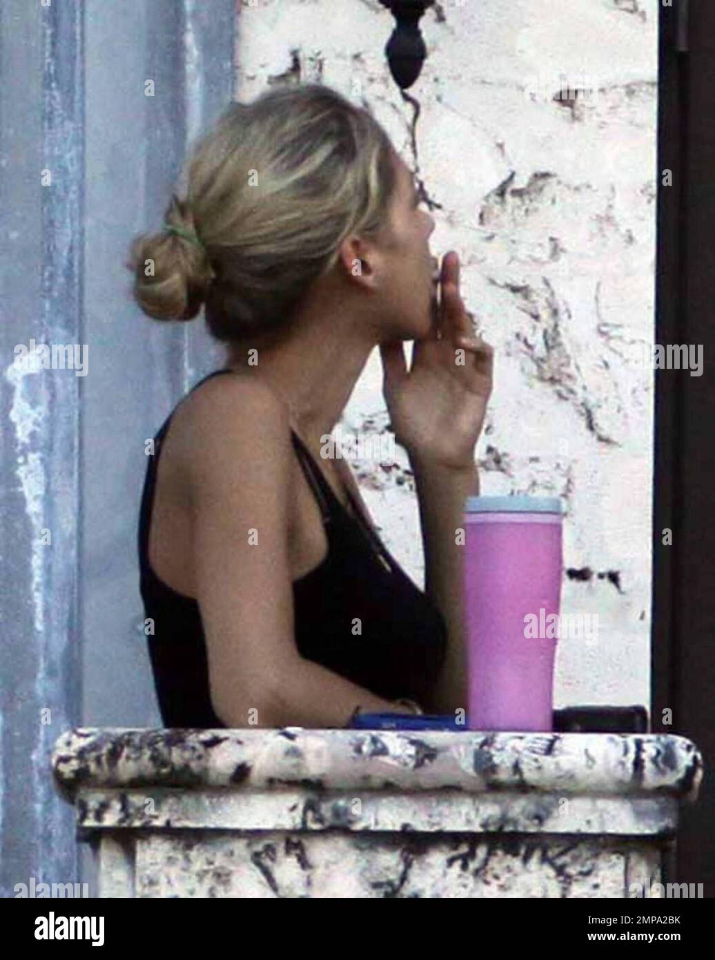 EXCLUSIVE!! Despite recent rumors of pregnancy, Anna Kournikova was spotted  on the balcony of her beleaguered home smoking a cigarette and looking at  her figure in the reflection of a glass door