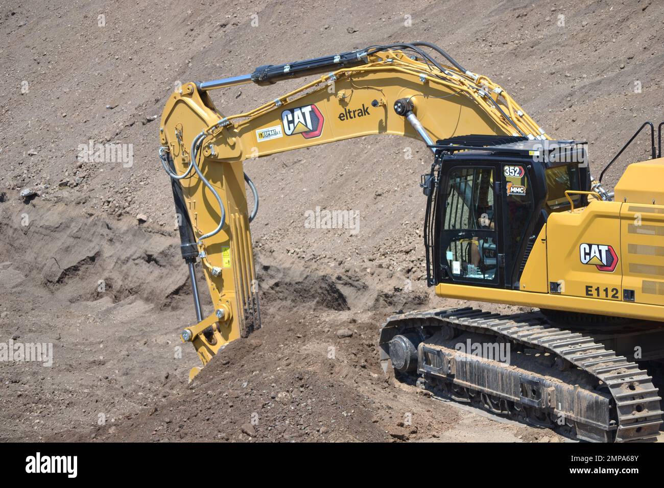 Caterpillar excavator working. Loading truck on huge mining site. Stock Photo