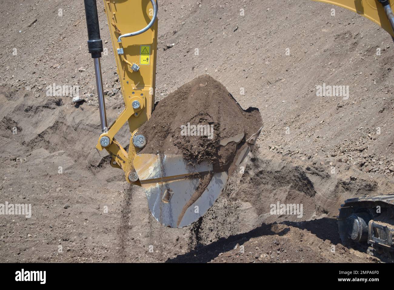 Excavator's bucket full with soil, ready to load the truck Stock Photo