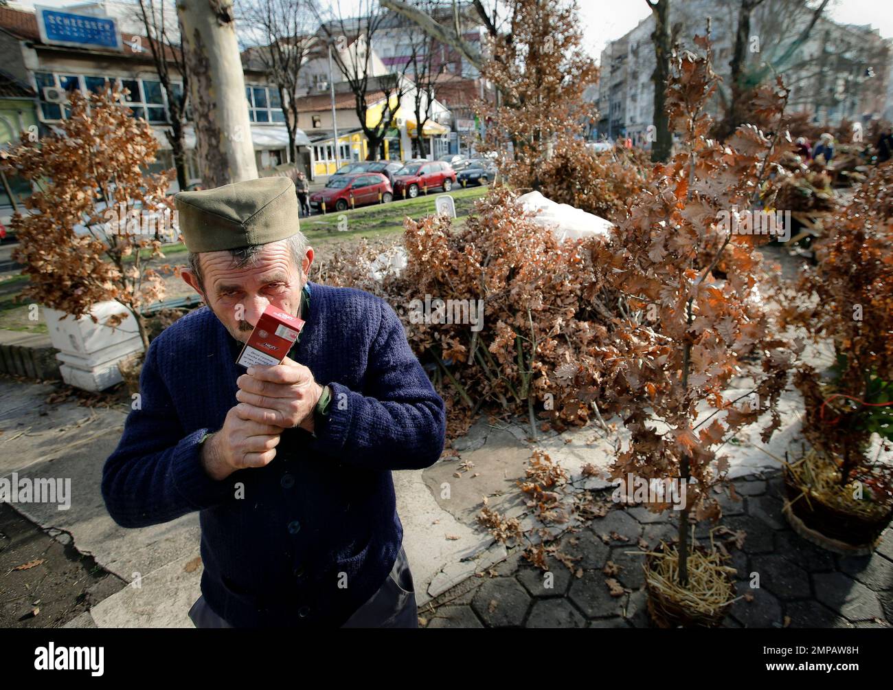 a-man-lights-up-a-cigarette-while-selling-dried-oak-branches-a