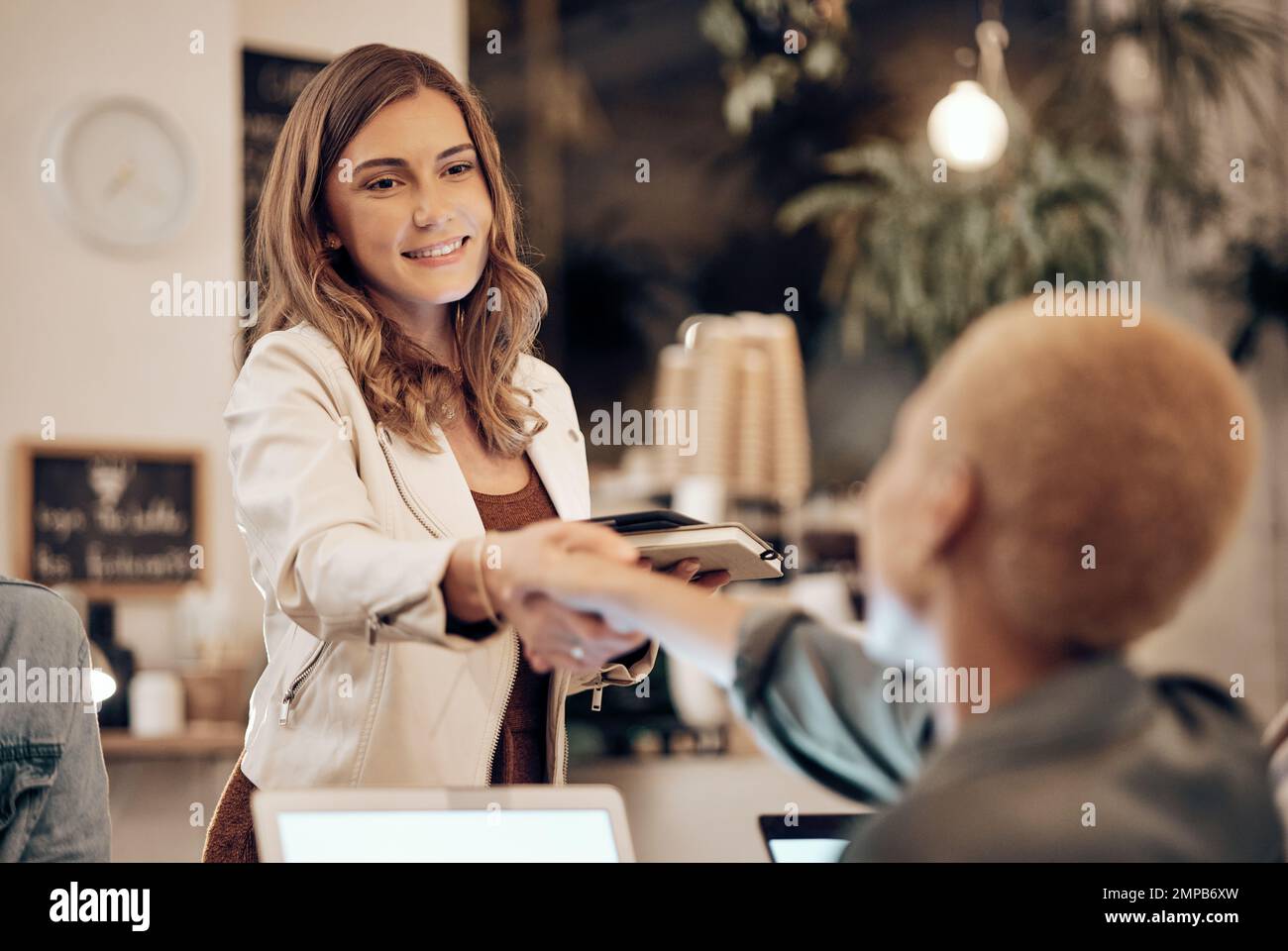 Handshake, coffee shop and service with a woman customer saying thank you to a waitress in a restaurant. Cafe, sale and welcome with a female consumer Stock Photo