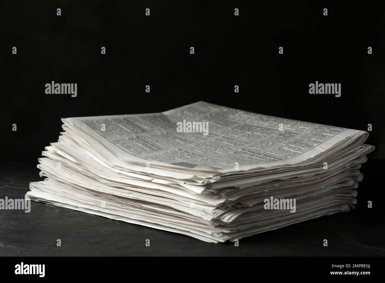 Stack of newspapers on dark stone table. Journalist's work Stock Photo