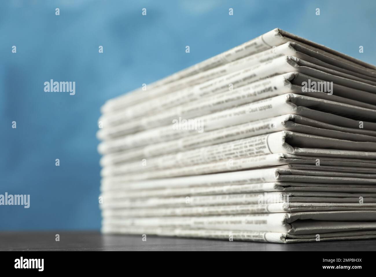 Stack of newspapers on blue background, closeup. Journalist's work Stock Photo