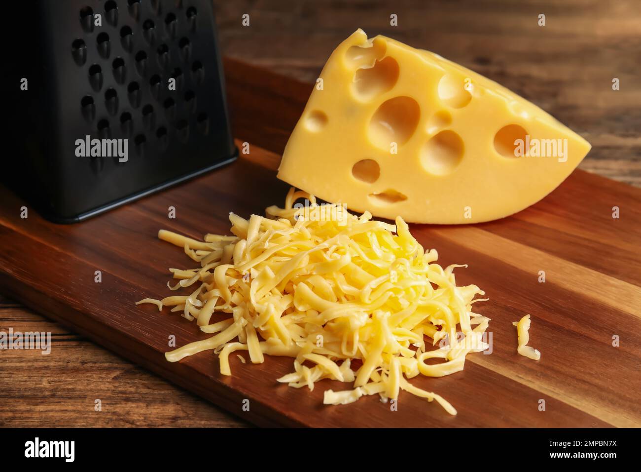 https://c8.alamy.com/comp/2MPBN7X/tasty-grated-and-whole-cheese-on-wooden-table-2MPBN7X.jpg
