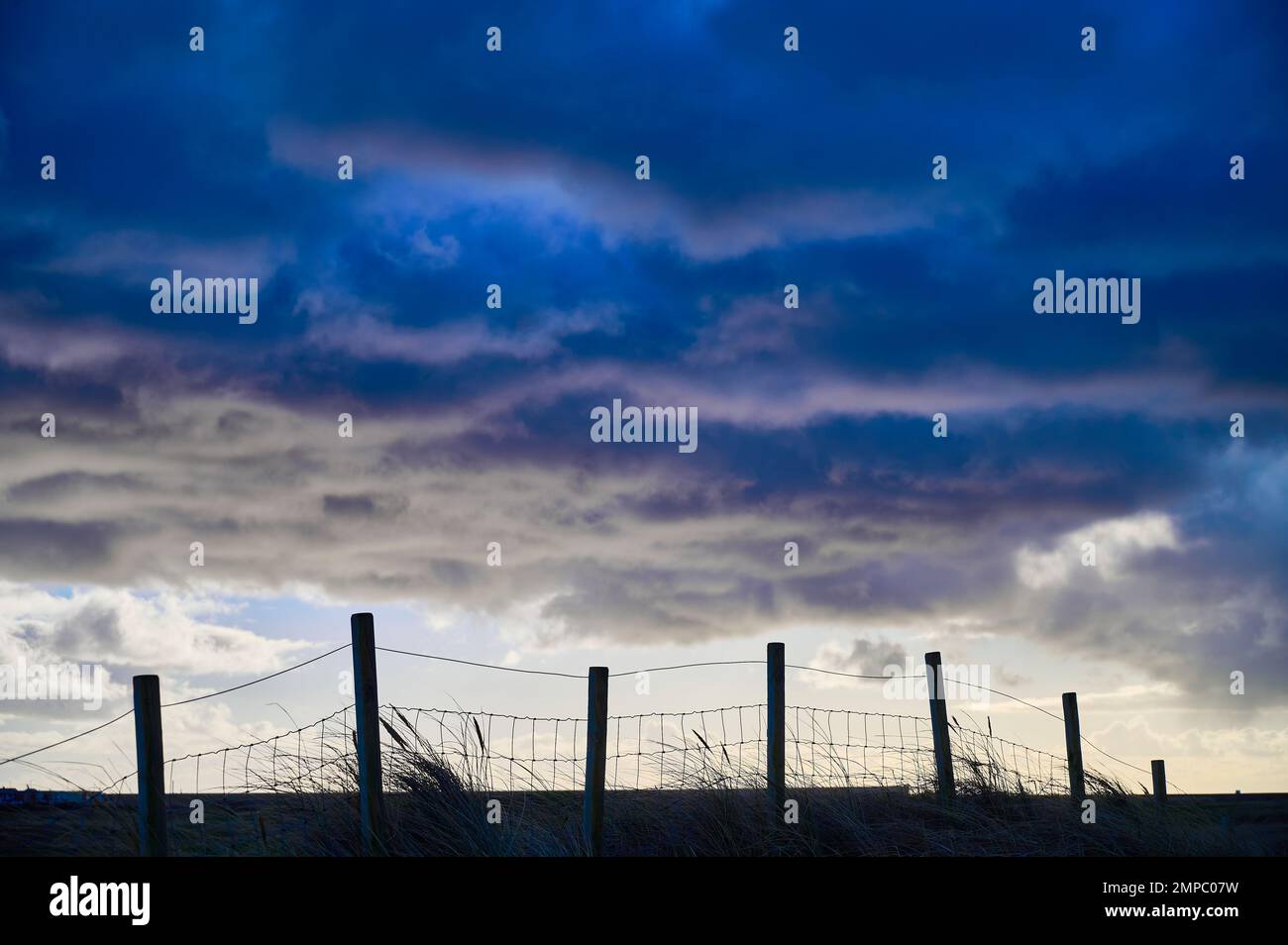 Fence silhouetted against storm clouds Stock Photo - Alamy