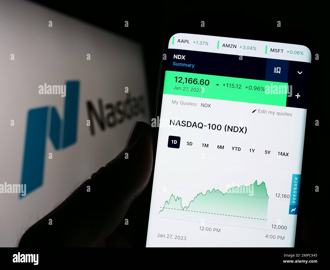 Person holding cellphone with webpage of US stock exchange Nasdaq on screen in front of business logo. Focus on center of phone display. Stock Photo
