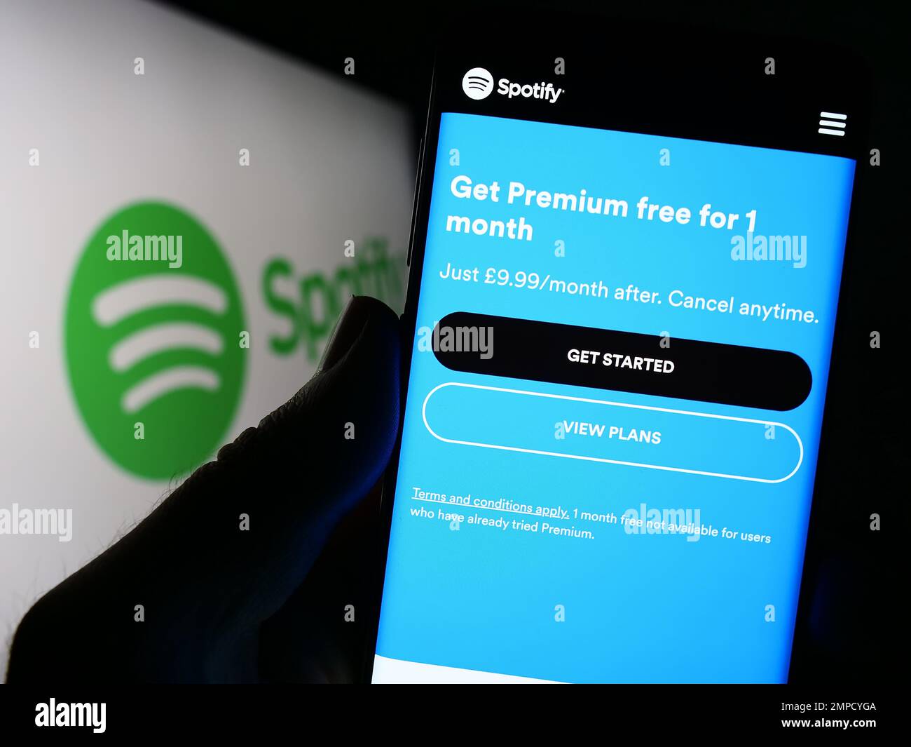 Person holding cellphone with webpage of music streaming company Spotify Technology S.A. on screen with logo. Focus on center of phone display. Stock Photo