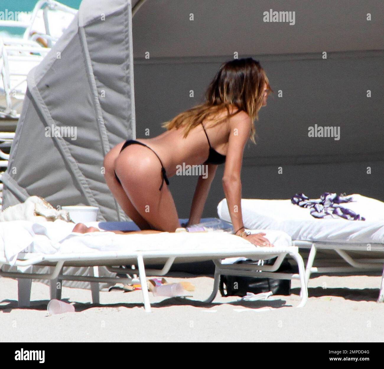 Bikini babe Belen Rodriguez appeared to have another bikini malfunction for the second day in a row. Yesterday her top had come adrift and today it seems her bottoms wouldn't behave. The Italian/Argentinian model relaxed beachside with pals and played in the surf. Miami, FL. 3/7/10. Stock Photo