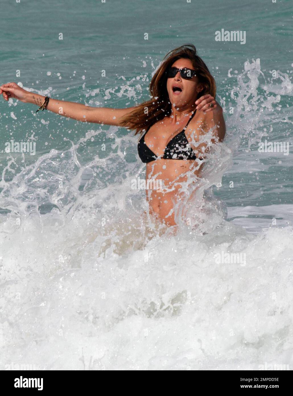 Bikini babe Belen Rodriguez appeared to have another bikini malfunction for the second day in a row. Yesterday her top had come adrift and today it seems her bottoms wouldn't behave. The Italian/Argentinian model relaxed beachside with pals and played in the surf. Miami, FL. 3/7/10.   . Stock Photo