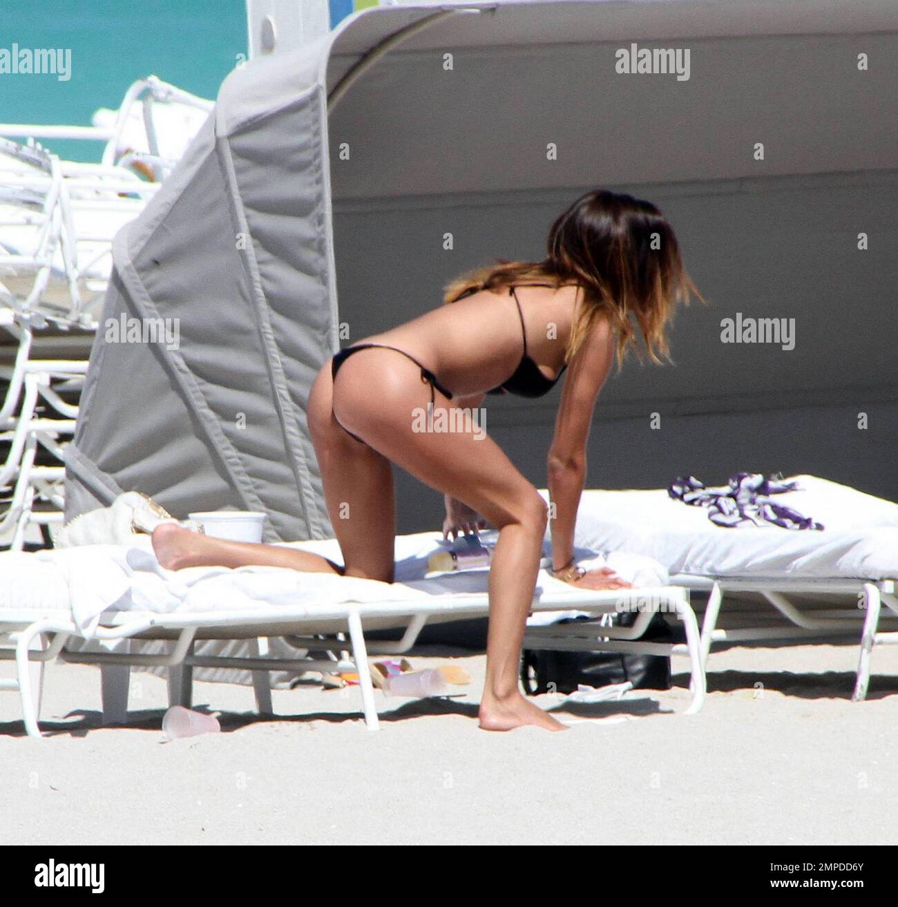 Bikini babe Belen Rodriguez appeared to have another bikini malfunction for the second day in a row. Yesterday her top had come adrift and today it seems her bottoms wouldn't behave. The Italian/Argentinian model relaxed beachside with pals and played in the surf. Miami, FL. 3/7/10.   . Stock Photo