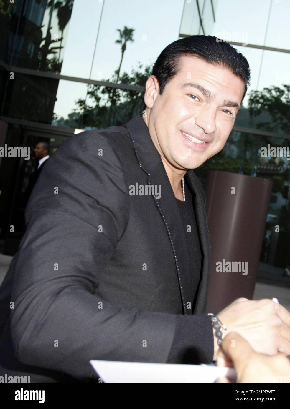 Actor Tamer Hassan smokes a cigarette as he signs autographs at the