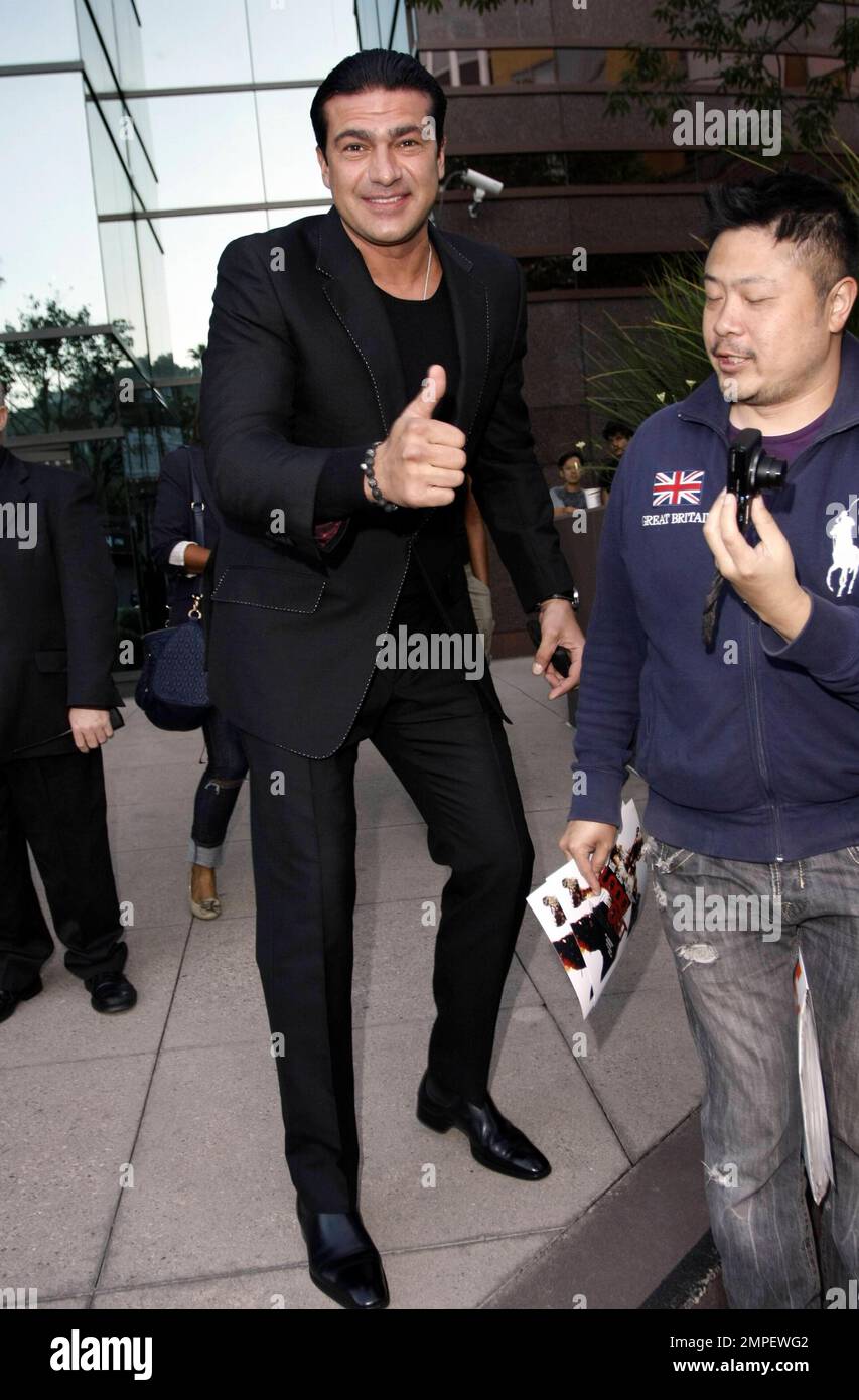 Actor Tamer Hassan smokes a cigarette as he signs autographs at the