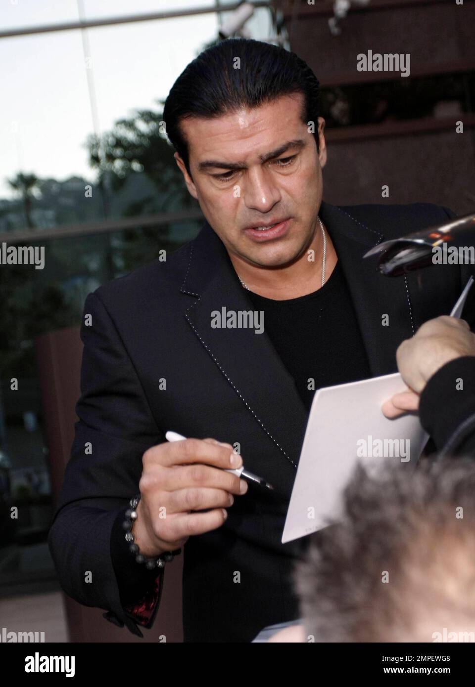 Actor Tamer Hassan smokes a cigarette as he signs autographs at the