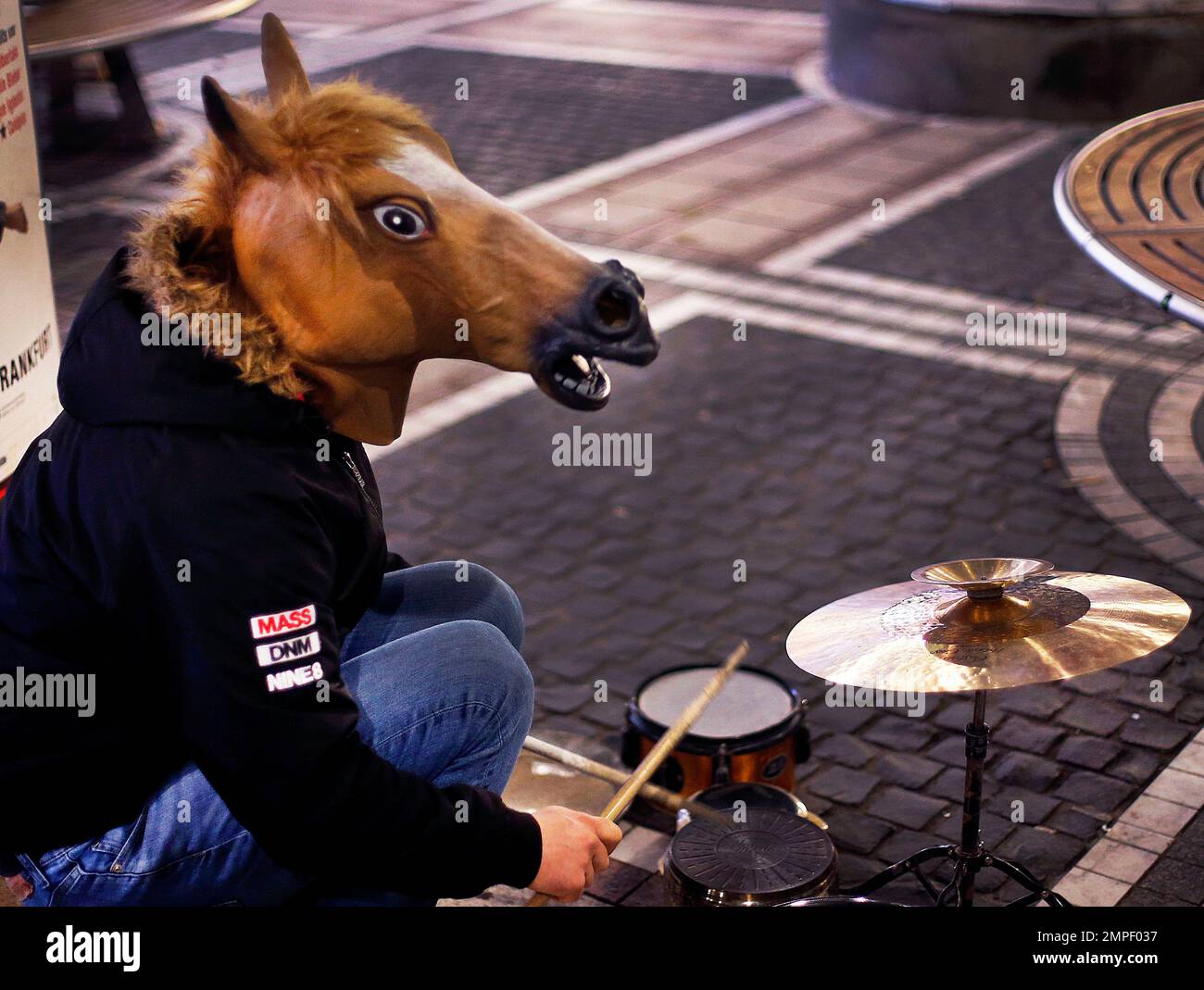 A drummer wears a horse mask as he performs in the main shopping street