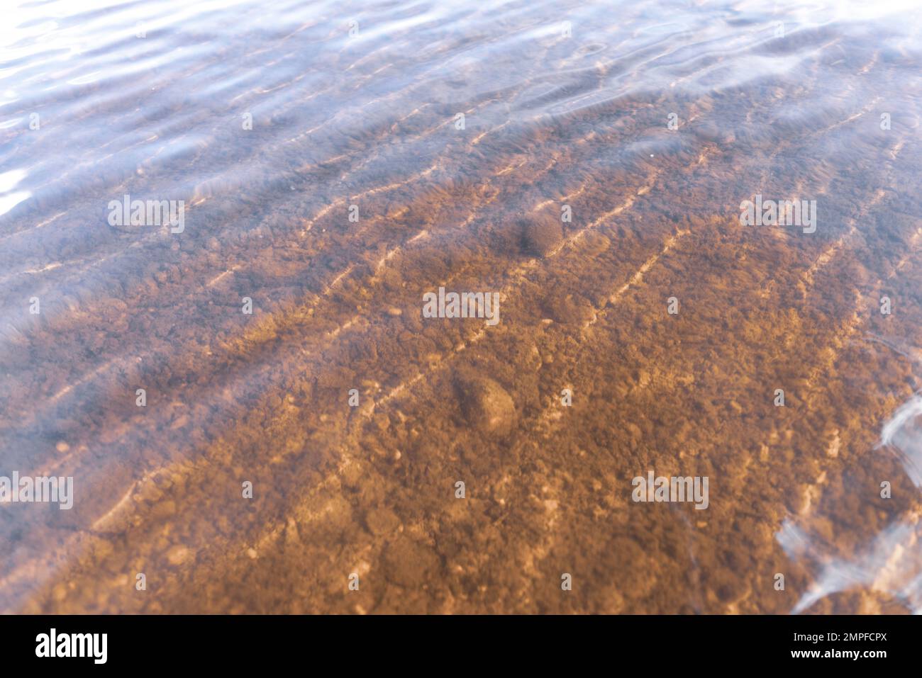 The bottom of the river through transparent water with light reflection ...