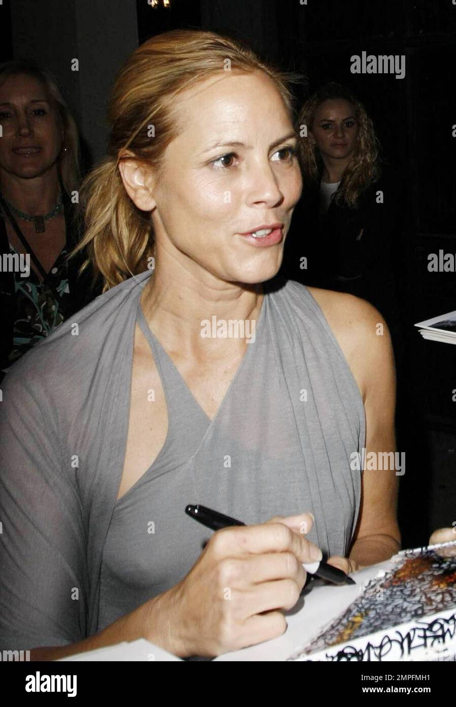 Maria Bello wears a grey slinky dress and appears to go braless