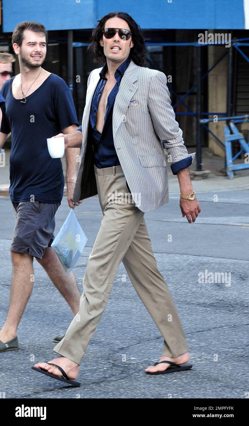 Russell Brand wears workout gear, including a sleeveless shirt that reads 'You'll go to hell for what your dirty mind is thinking,' as he heads to his trailer to change. He later emerges in a tan suit, black shirt and flip flops on the set of his new film, a remake of the 1981 hit 'Arthur.' In the film, he plays the role of Arthur, originally played by Dudley Moore. Brand is joined in the film by Helen Mirren, who plays his butler, a role that originally won Sir John Gielgud his only Oscar. Mirren was also spotted on set wearing a blue polka-dot head wrap, sunglasses, white top and pleated ski Stock Photo