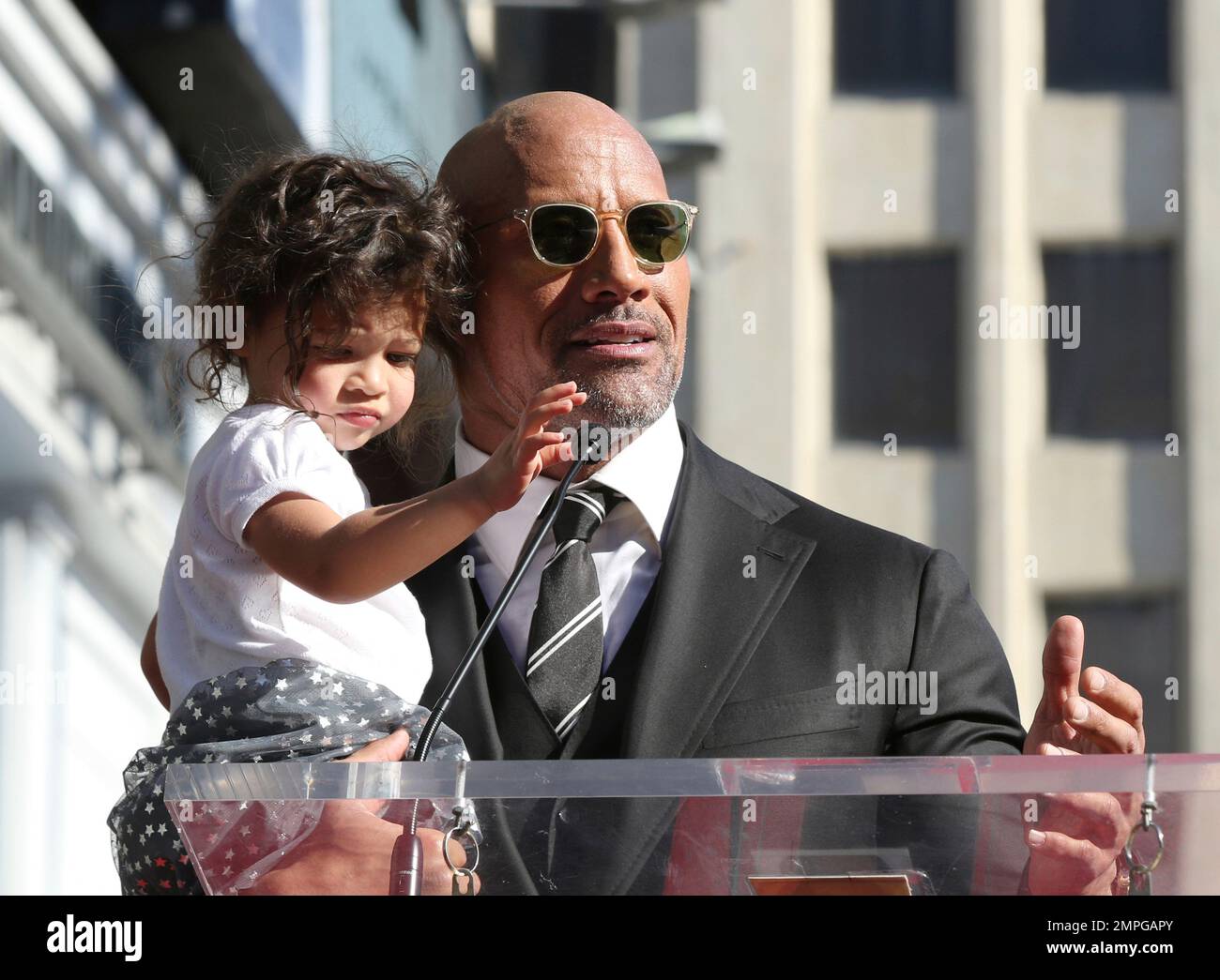 Dwayne Johnson speaks at his star ceremony while holding his daughter
