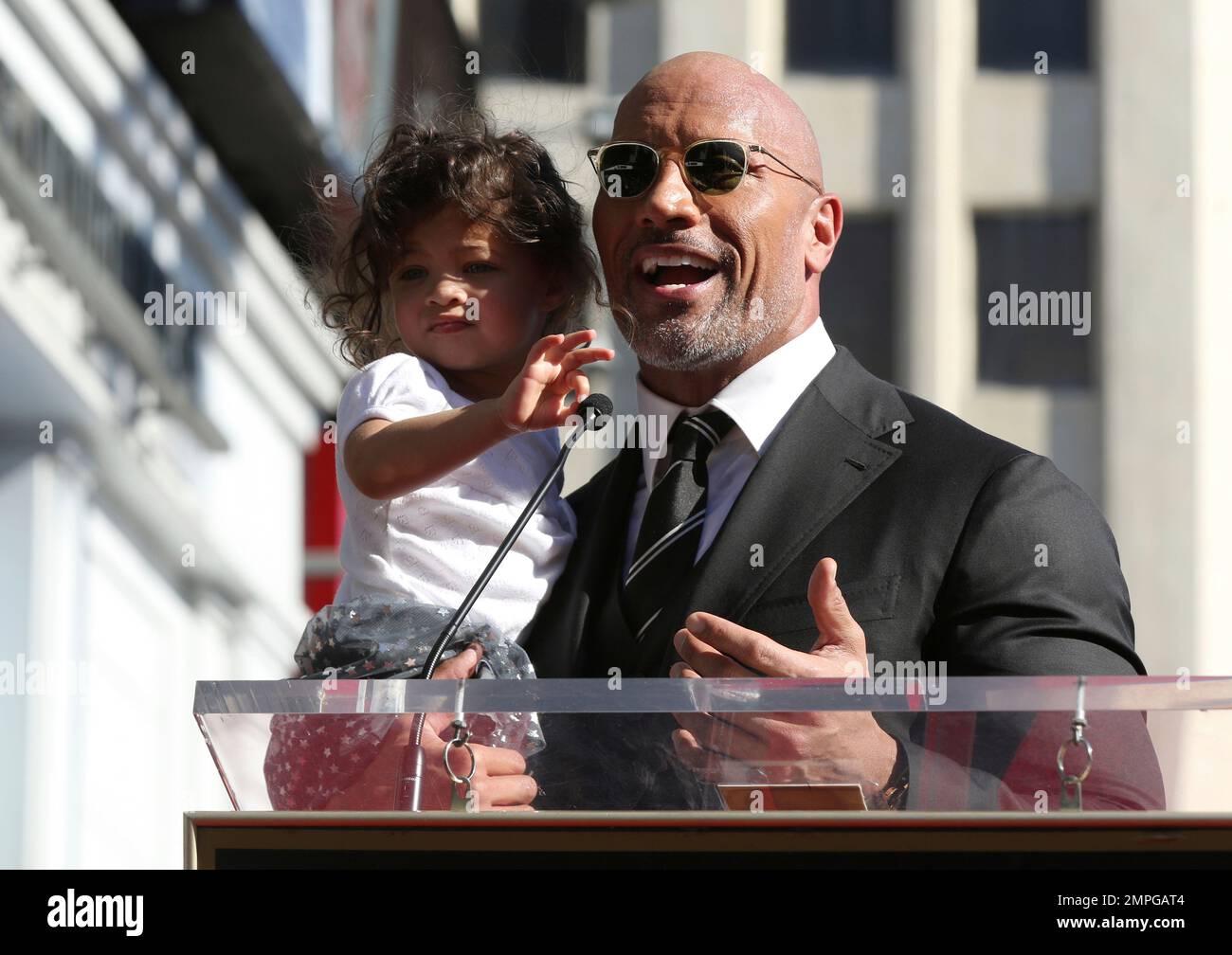 Dwayne Johnson speaks at his star ceremony while holding his daughter