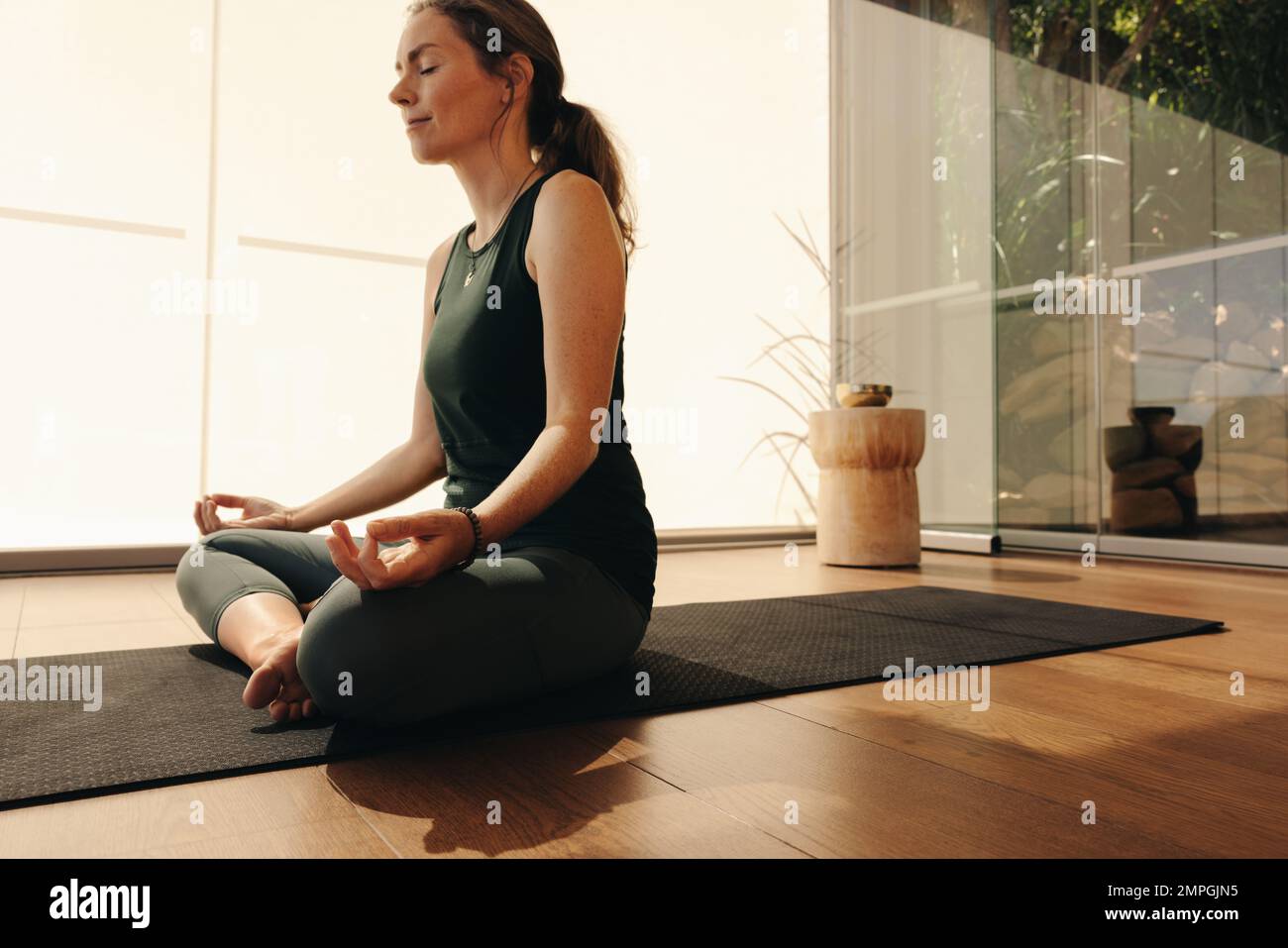 Senior woman meditating while practicing hatha yoga. Mature woman doing a relaxation exercise while sitting in easy pose. Woman following a healthy wo Stock Photo