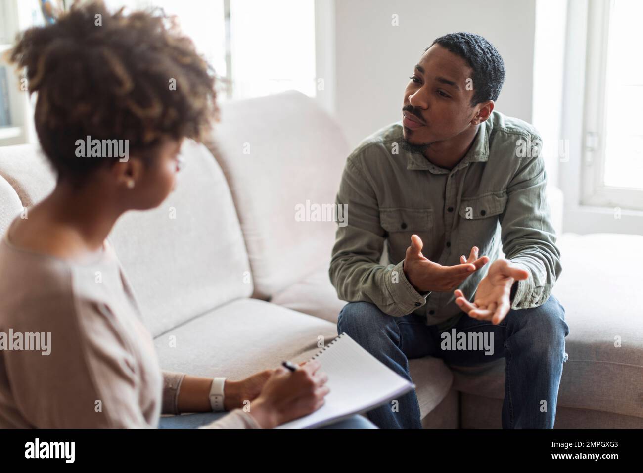 Confused black guy sharing thoughts with psychologist Stock Photo