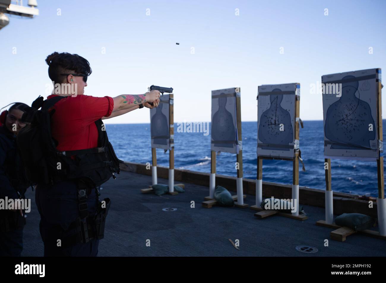 Gunner's Mate Seaman Anna Hawkins, from Magalia, California, assigned to the first-in-class aircraft carrier USS Gerald R. Ford's (CVN 78) weapons department, fires the M9 pistol during a small arms live fire gunnery exercise on the ship’s aircraft elevator, Oct. 15, 2022. The Gerald R. Ford Carrier Strike Group (GRFCSG) is deployed in the Atlantic Ocean, conducting training and operations alongside NATO Allies and partners to enhance integration for future operations and demonstrate the U.S. Navy’s commitment to a peaceful, stable and conflict-free Atlantic region. Stock Photo