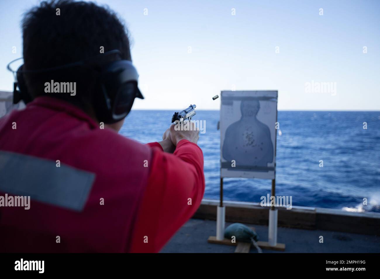 Seaman Nathan Mazza, from Sterling, Virginia, assigned to the first-in-class aircraft carrier USS Gerald R. Ford's (CVN 78) weapons department, fires the M9 pistol during a small arms live fire gunnery exercise on the ship’s aircraft elevator, Oct. 15, 2022. The Gerald R. Ford Carrier Strike Group (GRFCSG) is deployed in the Atlantic Ocean, conducting training and operations alongside NATO Allies and partners to enhance integration for future operations and demonstrate the U.S. Navy’s commitment to a peaceful, stable and conflict-free Atlantic region. Stock Photo