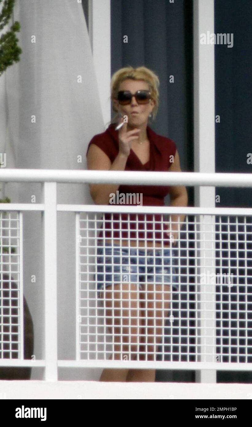 Singer Britney Spears enjoys one of several smoke breaks on the balcony of her hotel suite with her sons playing in the background. Her brother Bryan also comes out and hangs out with her, pointing out some Miami scenery. Miami, FL. 9/3/09. Stock Photo