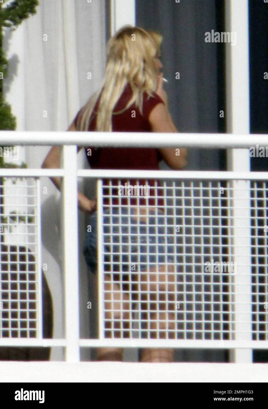 Singer Britney Spears enjoys one of several smoke breaks on the balcony of her hotel suite with her sons playing in the background. Her brother Bryan also comes out and hangs out with her, pointing out some Miami scenery. Miami, FL. 9/3/09. Stock Photo