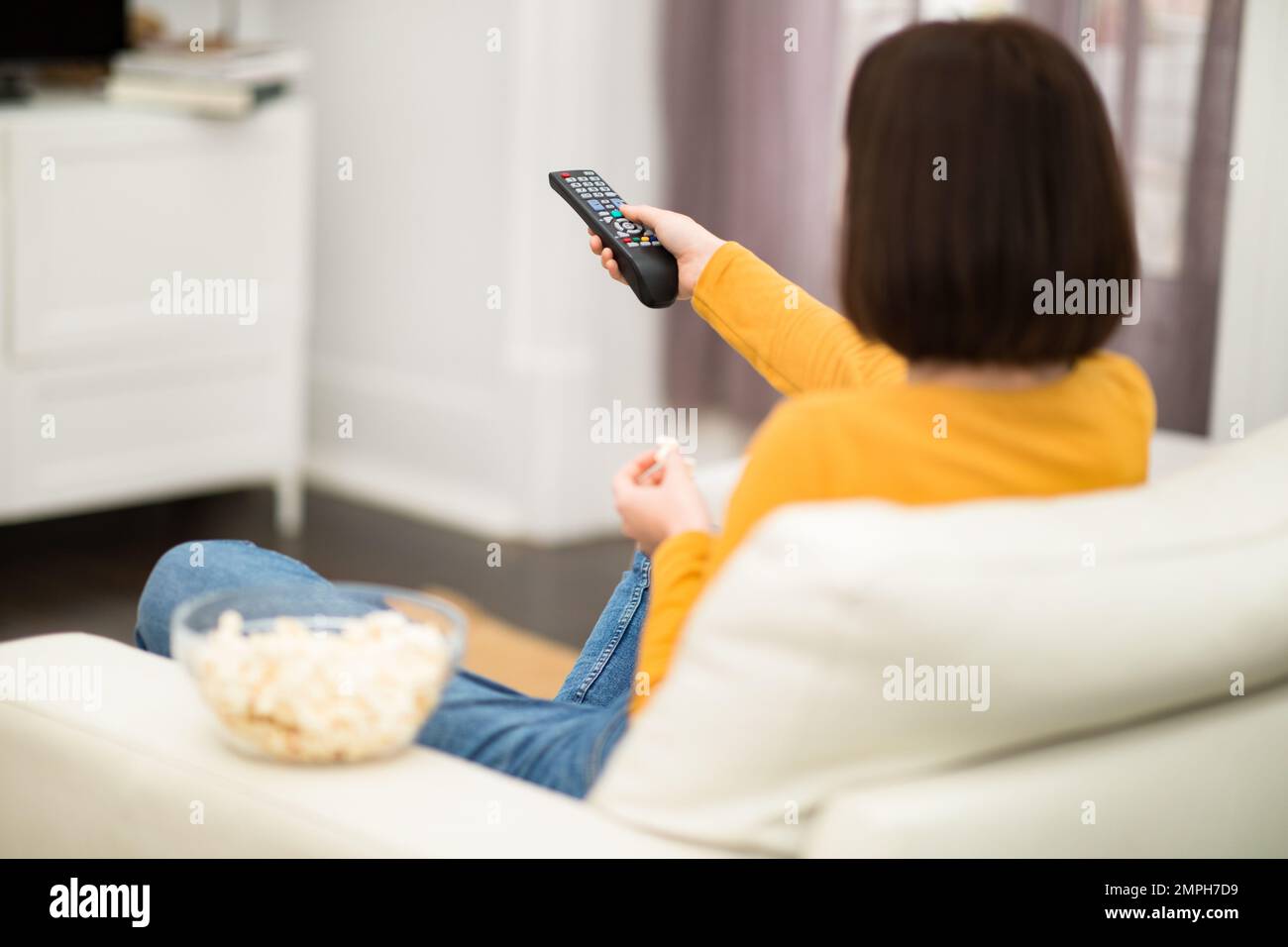Unrecognizable brunette woman switching channels on TV Stock Photo