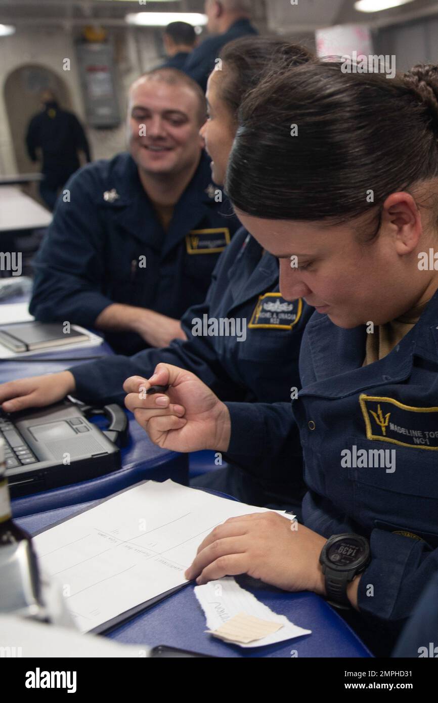 221019-N-IL330-2036 PHILIPPINE SEA (Oct. 19, 2022) – Navy Counselor 1st Class Madeline Torres, from Perth Amboy, New Jersey, grades teams score sheets during a trivia contest on the mess decks aboard amphibious assault carrier USS Tripoli (LHA 7) Oct. 19, 2022. Tripoli is operating in the U.S. 7th Fleet area of operations to enhance interoperability with allies and partners and serve as a ready response force to defend peace and maintain stability in the Indo-Pacific region. Stock Photo