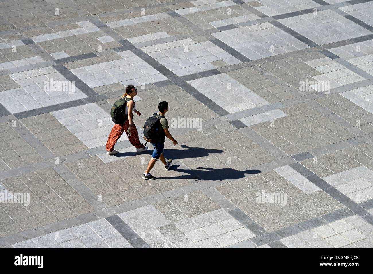 View from above two people walking in public square with shadows Stock Photo