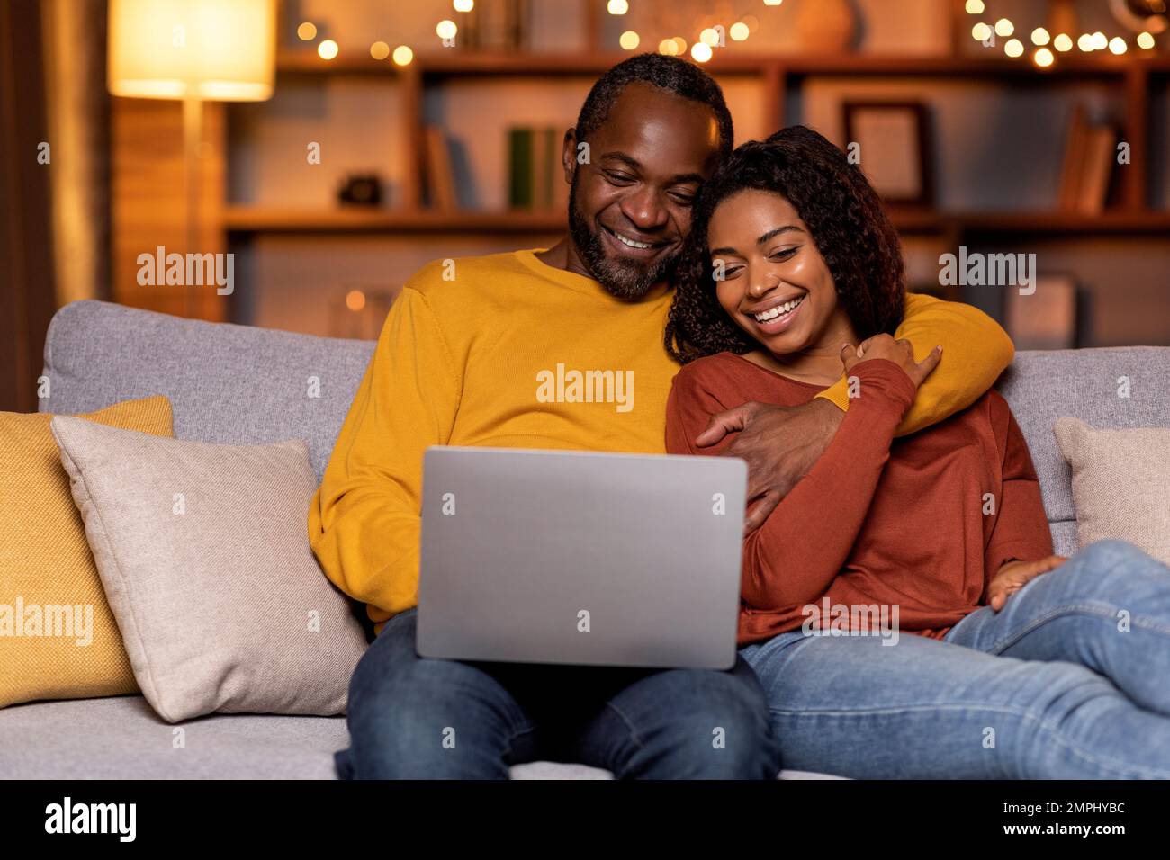 Happy african american spouses sitting on couch, using computer Stock ...
