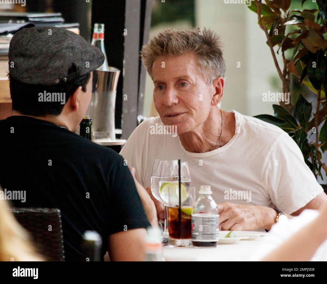 In a simple white t-shirt American fashion designer Calvin Klein enjoys a late afternoon lunch with a male companion. Miami, FL. 11/27/10. Stock Photo