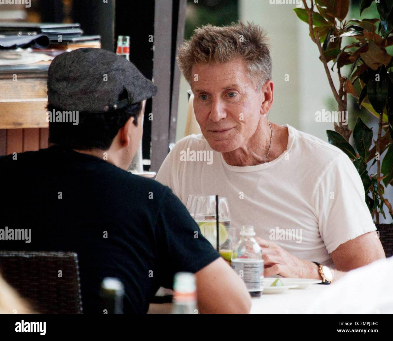 In a simple white t-shirt American fashion designer Calvin Klein enjoys a late afternoon lunch with a male companion. Miami, FL. 11/27/10. Stock Photo