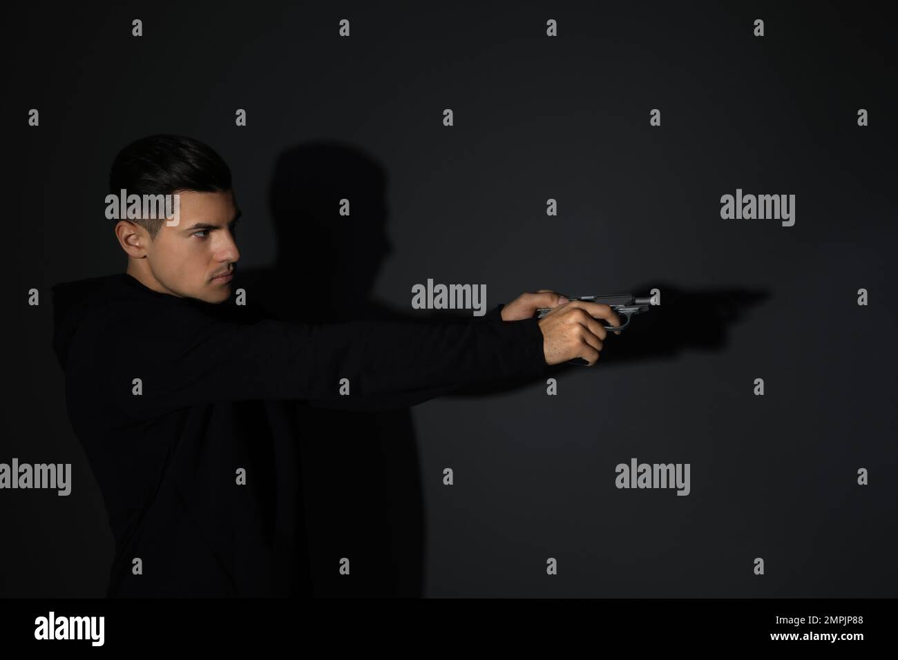 Professional killer with gun on black background Stock Photo - Alamy