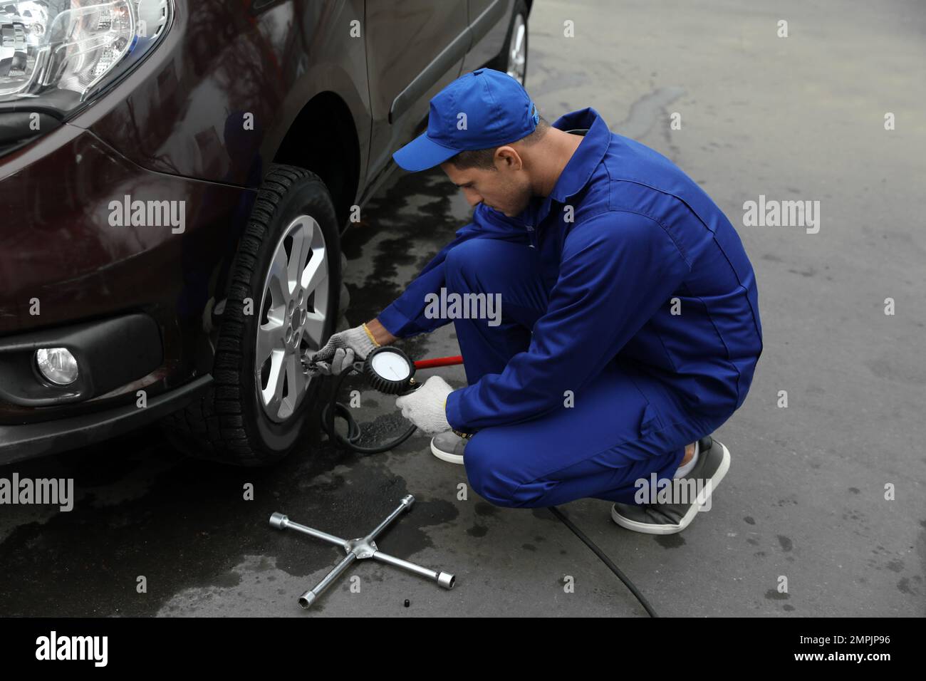 Worker checking tire pressure in car wheel at service station Stock ...
