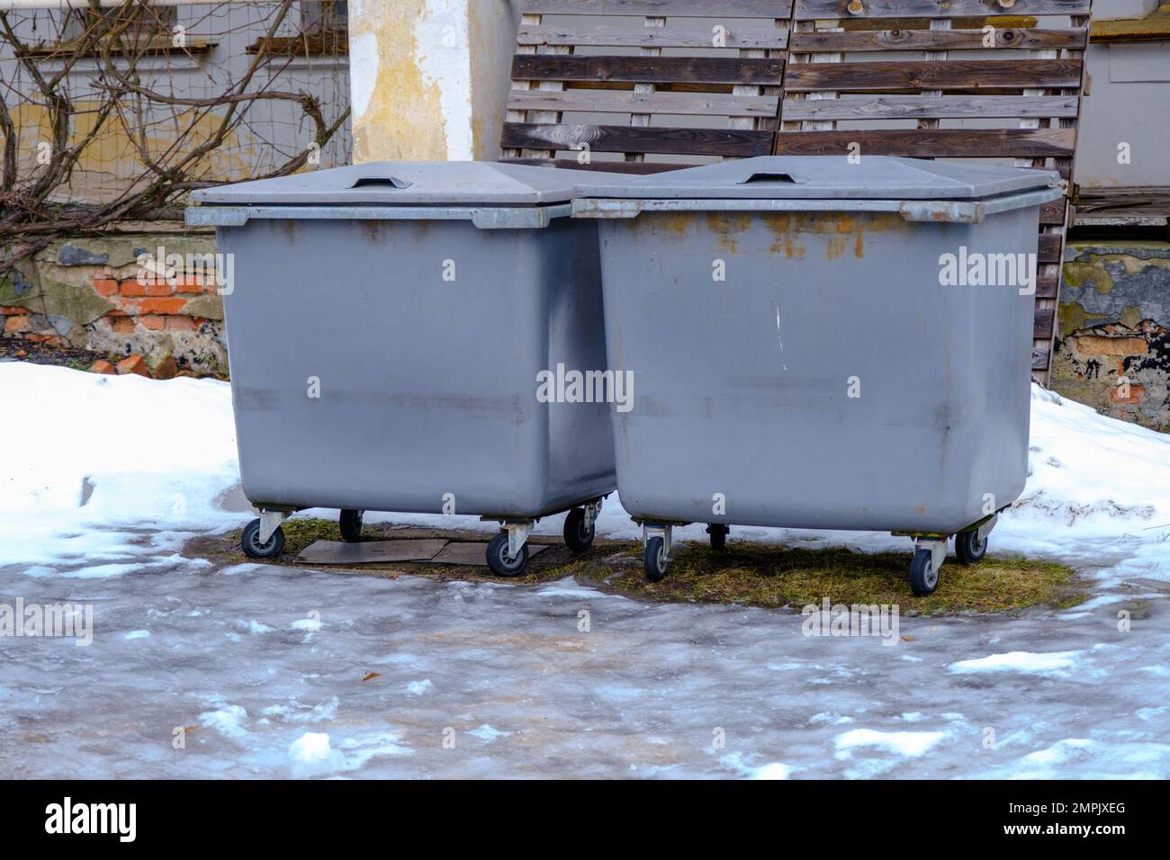 https://c8.alamy.com/comp/2MPJXEG/plastic-large-trash-cans-with-lids-and-trash-inside-against-an-orange-brick-wall-large-gray-plastic-trash-cans-on-a-city-street-waste-containers-re-2MPJXEG.jpg