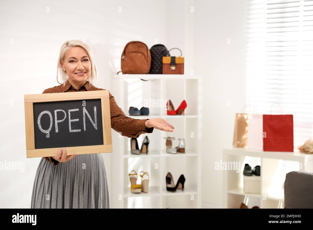 Female business owner holding OPEN sign in boutique. Space for text Stock Photo
