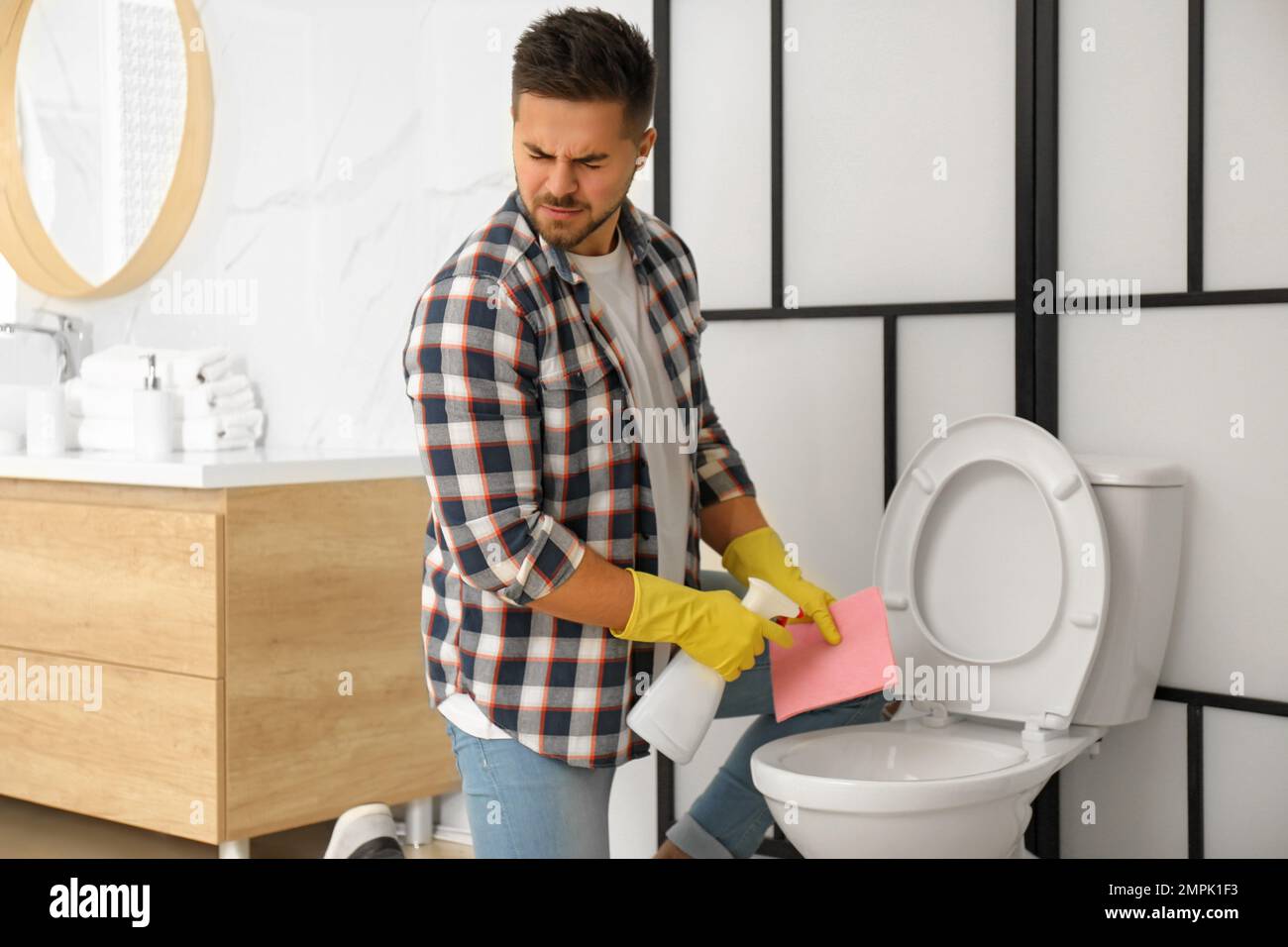 Young man feeling disgust while cleaning toilet bowl in bathroom Stock Photo Alamy